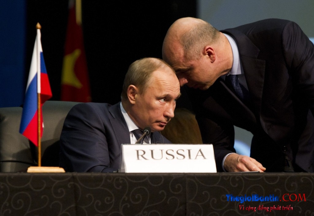 An aide speaks to Russian President Vladimir Putin during closing remarks at the fifth BRICS Summit in Durban
