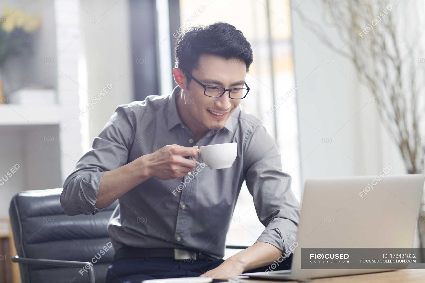 Asian man working with laptop and coffee in office — indoors, drink - Stock Photo | #178421832